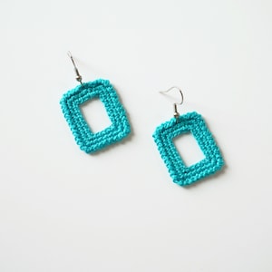 May include: A pair of turquoise crocheted square earrings with silver hooks.