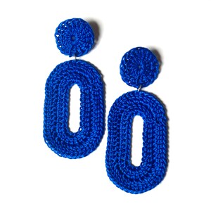 May include: A pair of blue crocheted earrings with oval shapes and small round accents.