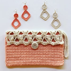 May include: A crocheted clutch bag with a beige crocheted trim and a pink crocheted body. The bag has a small, beige crocheted flower on the front. The bag is accompanied by three pairs of crocheted earrings, two in pink and one in beige.