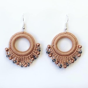 May include: A pair of crocheted earrings with a copper-colored fringe and silver beads.