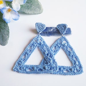 May include: A pair of light blue crocheted triangle earrings. The earrings are made with a delicate, openwork design.