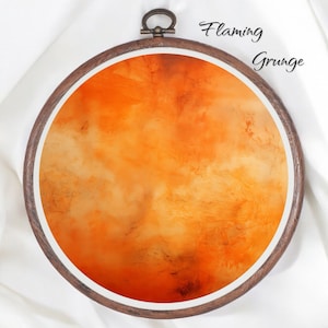 Puede incluir: Un aro de bordado redondo con un diseño abstracto naranja y amarillo llameante. El texto "Flaming Grunge" está escrito encima del aro.