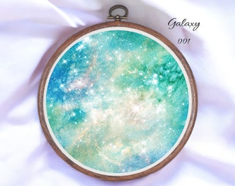 May include: A round wooden embroidery hoop with a colorful galaxy-themed design. The design features a swirling nebula with shades of blue, green, and white, and is dotted with sparkling stars.