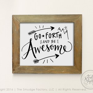 May include: A framed print with a white background and black text that reads "GO FORTH AND BE AWESOME". The text is in a handwritten style with arrows and a mountain range graphic. The frame is a light brown wood.