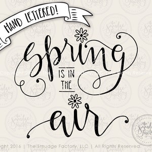 May include: Black and white hand-lettered calligraphy design with the text "Spring is in the air". The design includes stylized flowers.