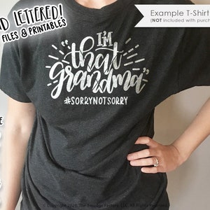Può includere: Una maglietta grigia scura con un design bianco che dice "I'm that grandma" con l'hashtag "#sorrynotsorry" sotto.