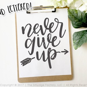 May include: A white clipboard with a black background and the text "never give up" written in black cursive font with an arrow pointing to the right. The text is hand-lettered.