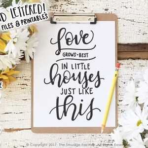 Peut inclure: Un presse-papiers blanc avec une citation manuscrite en noir et blanc qui dit "L'amour grandit mieux dans les petites maisons comme celle-ci". La citation est entour&eacute;e de marguerites blanches et de tournesols jaunes.