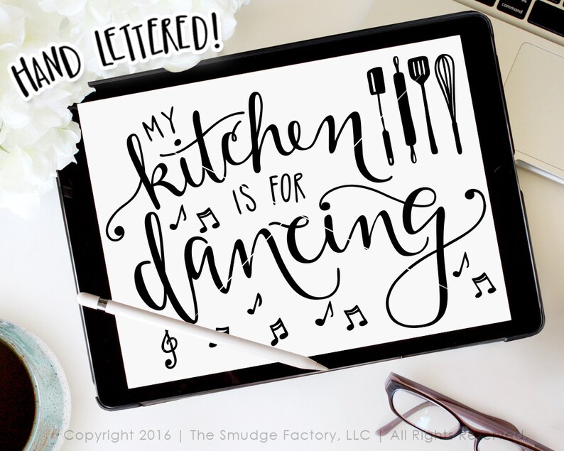 May include: Black and white hand-lettered design on a white background. The text reads "My kitchen is for dancing" with musical notes and kitchen utensils. The text "HAND LETTERED!" is in a smaller font at the top of the image.