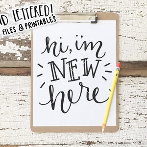 May include: A white sheet of paper with black text that reads "hi, im NEW here" on a clipboard with a yellow pencil. The background is a whitewashed wooden surface.
