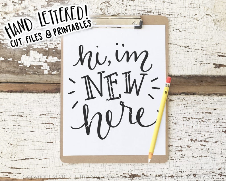 May include: A white sheet of paper with black text that reads "hi, im NEW here" on a clipboard with a yellow pencil. The background is a whitewashed wooden surface.