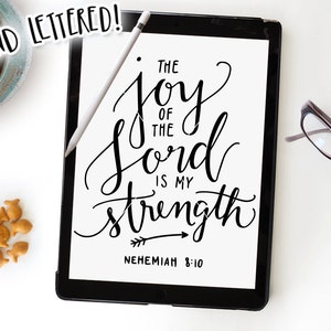 May include: A digital tablet displaying a black and white hand-lettered quote, "The joy of the Lord is my strength", with the scripture reference "Nehemiah 8:10" below.