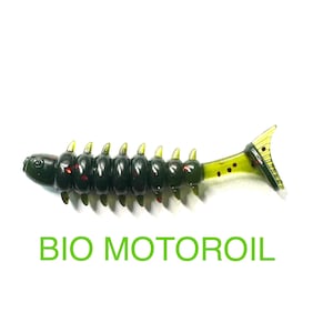 May include: A dark green and yellow fishing lure with a segmented body and a tail fin. The lure has a series of yellow spikes along its back and the text "BIO MOTOROIL" in green.