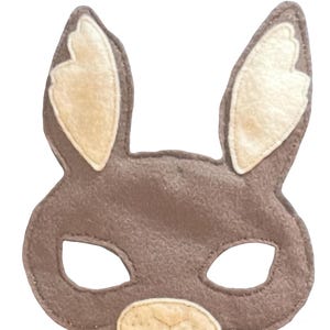 May include: A brown felt bunny mask with large ears and eye openings. The inside of the ears and the nose are a lighter tan color. This mask is designed for children's dress-up and costume play.