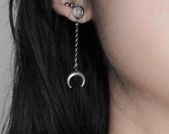 May include: A silver crescent moon dangle earring with a small silver bead and a chain.