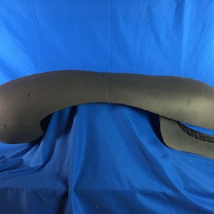 May include: A black foam alien head sculpture with markings and details. The head is in two pieces, with the top half resting on the bottom half.