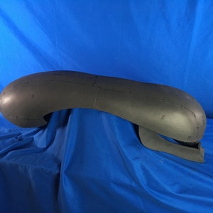 May include: A black foam model of a head with markings for sewing. The model is shaped like an alien head with a large, rounded top and a smaller, pointed chin.