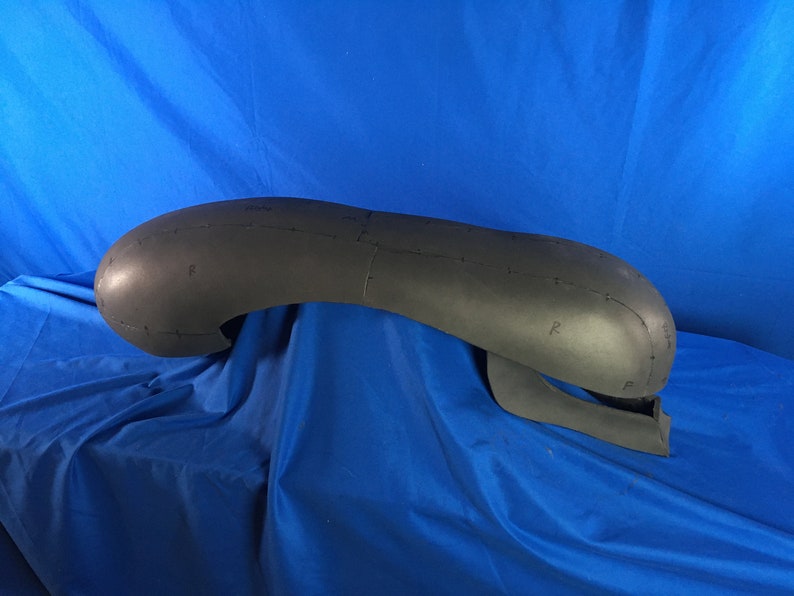 May include: A black foam model of a head with markings for sewing. The model is shaped like an alien head with a large, rounded top and a smaller, pointed chin.