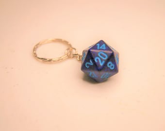 Op de afbeelding: Een blauwe 20-zijdige dobbelsteen sleutelhanger met lichtblauwe nummers. De dobbelsteen is bevestigd aan een zilveren sleutelhanger.