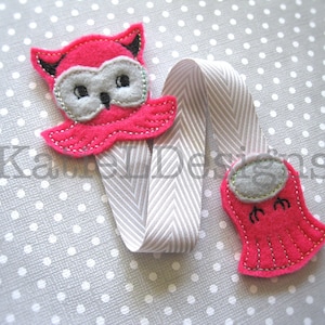 May include: Pink felt owl bookmark with a gray felt face and a white ribbon. The owl has a small beak and two small feet.