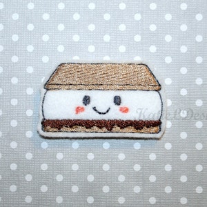 May include: A brown, white, and chocolate embroidered patch of a smiling s'more. The s'more has a brown graham cracker, a white marshmallow, and a chocolate layer.