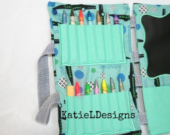 May include: A teal crayon roll-up with a blue and white patterned fabric, featuring pockets for crayons and a chalkboard. The roll-up has a chevron patterned strap and the text "KatieLDesigns".