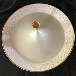 May include: White ceramic serving dish with a gold rim and a central pedestal. The dish has a raised, embossed pattern.