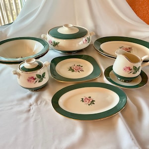 May include: A set of vintage green and white china with a rose pattern. The set includes a covered casserole dish, two bowls, two plates, a creamer, and a sugar bowl.