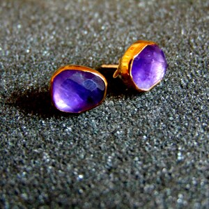 Peut inclure: Une paire de boucles d'oreilles en or avec des pierres pr&eacute;cieuses d'am&eacute;thyste violettes. Les boucles d'oreilles sont de style simple et moderne.