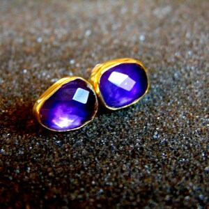 Peut inclure: Une paire de boucles d'oreilles en or avec des accents de pierres pr&eacute;cieuses violettes. Les boucles d'oreilles sont de forme carr&eacute;e et ont une finition polie.