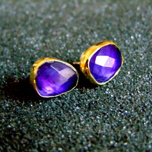Peut inclure: Une paire de boucles d'oreilles en or avec des pierres pr&eacute;cieuses d'am&eacute;thyste violettes. Les boucles d'oreilles sont de style simple et moderne.