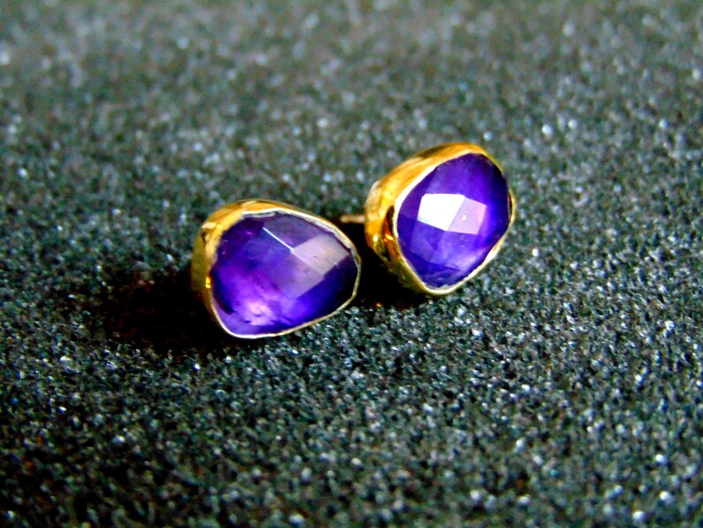 Peut inclure: Une paire de boucles d'oreilles en or avec des pierres pr&eacute;cieuses d'am&eacute;thyste violettes. Les boucles d'oreilles sont de style simple et moderne.