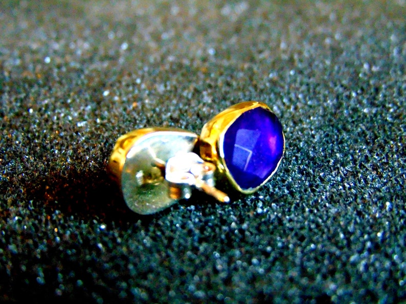 Peut inclure: Une boucle d'oreille en or avec une pierre pr&eacute;cieuse violette. La boucle d'oreille est de style clou avec une tige et un fermoir.