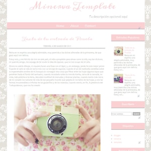 May include: A green and white vintage camera with the word "Dreamer" on the front. The camera is being held by a person wearing a pink floral dress. The image has a blog post about a blog entry titled "Texto de tu entrada de Prueba" with a quote about the beauty of nature.