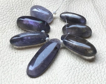 May include: A strand of seven oval-shaped, dark purple amethyst gemstone beads. The beads are smooth and polished, with a slight sheen.
