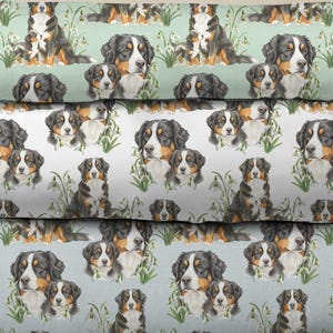 May include: Three stacks of fabric with Bernese Mountain Dog patterns in mint green, white, and blue. The fabric features watercolor illustrations of the dogs and flowers. Text on the image reads "Mockup view. You can request any color background. Message me."
