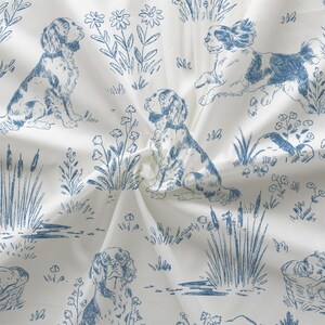 May include: White fabric with a blue toile pattern featuring dogs, flowers, and foliage. The dogs are depicted in various poses, including sitting and running. The design has a classic, vintage aesthetic.