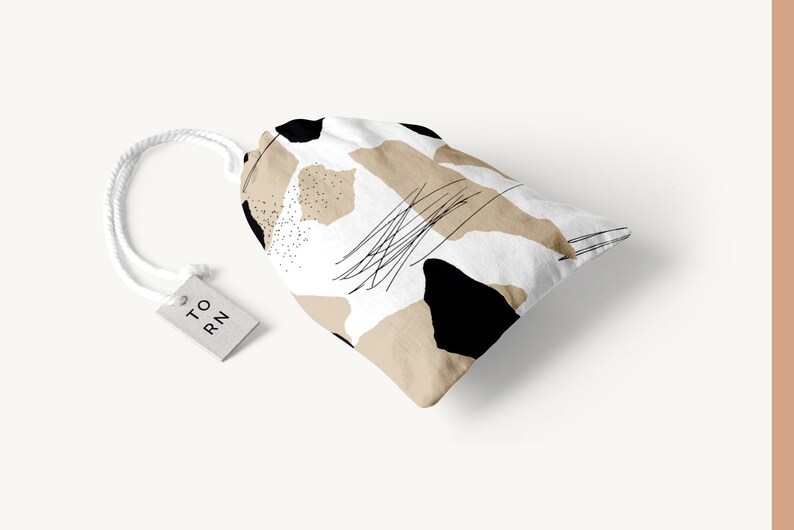 May include: A white drawstring bag with a black and beige abstract pattern. The bag has a white tag with the text "TO RN" on it.