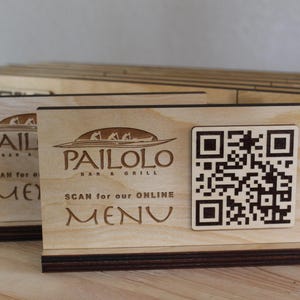 K&ouml;nnte beinhalten: Ein Schild aus Holz mit dem Text "Pailolo Bar & Grill" und einem QR-Code mit der Aufschrift "Scan for our online menu".
