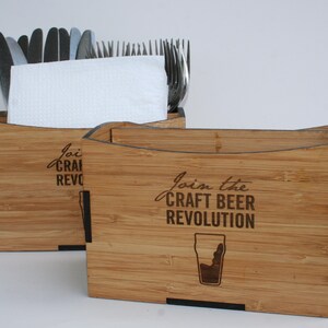 May include: Two wooden utensil holders with black trim. The holder on the left has the text "Join the Craft Beer Revolution" engraved on the front. The holder on the right has the text "Join the Craft Beer Revolution" engraved on the front.