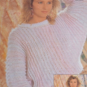 May include: A white and pink knitted jumper with a loose fit and a round neckline. The jumper has a delicate, openwork pattern.