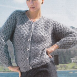 May include: A gray knitted cardigan with a cable knit pattern and button closure.