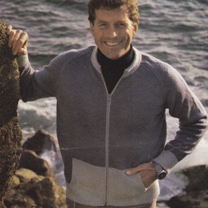 Può includere: Un maglione con zip in maglia grigia e beige con collo alto. Il maglione ha una fascia beige a contrasto sul fondo e una chiusura con zip.