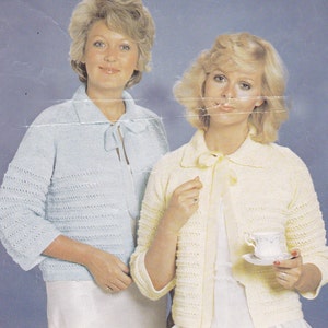 Op de afbeelding: Twee vrouwen dragen gebreide vesten met een strik om de hals. Het vest aan de linkerkant is lichtblauw en het vest aan de rechterkant is geel.