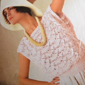 May include: A woman wearing a white hat and a pink crocheted top with a white beaded necklace.