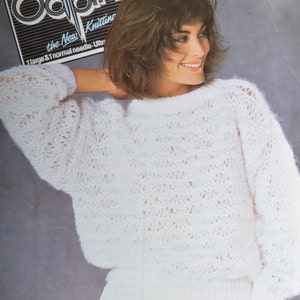 May include: A white knitted jumper with a loose fit and a delicate openwork pattern. The jumper is worn by a woman with brown hair. The image includes the text "Oddpins the New Knitting 1 large & 1 normal needle - Ultra"