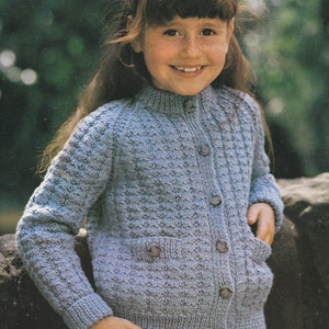 Könnte beinhalten: Ein hellblauer Strickcardigan mit Knopfleiste und zwei Taschen. Der Cardigan hat ein strukturiertes Strickmuster.