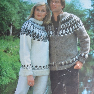 Può includere: Una coppia indossa maglioni abbinati con un motivo tradizionale scandinavo. I maglioni sono bianchi con accenti neri, grigi e marroni. Il maglione dell'uomo è un cardigan con bottoni. Il maglione della donna è a collo alto.