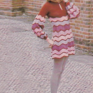 May include: A pink and purple striped crochet dress with long sleeves and a high neckline. The dress is being worn by a person with long blonde hair.