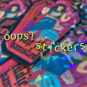 May include: A close-up of a stack of colorful holographic stickers with the text "oops!" and "stickers" on them. The stickers feature a cartoon character with a pink and blue outfit.